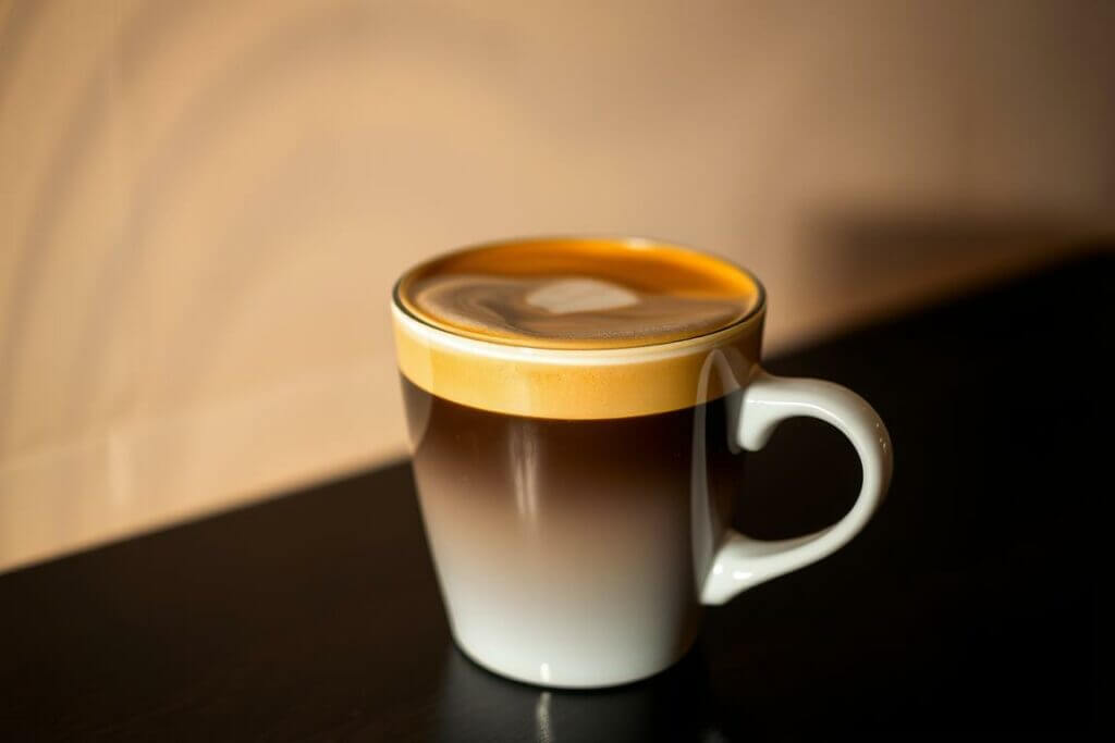 A delicate espresso macchiato in a classic white ceramic cup, set against a softly blurred backgrou