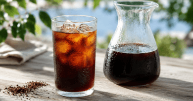 Cold Brew Kaffee im Glas mit Eis neben einer Karaffe und grob gemahlenem Kaffee